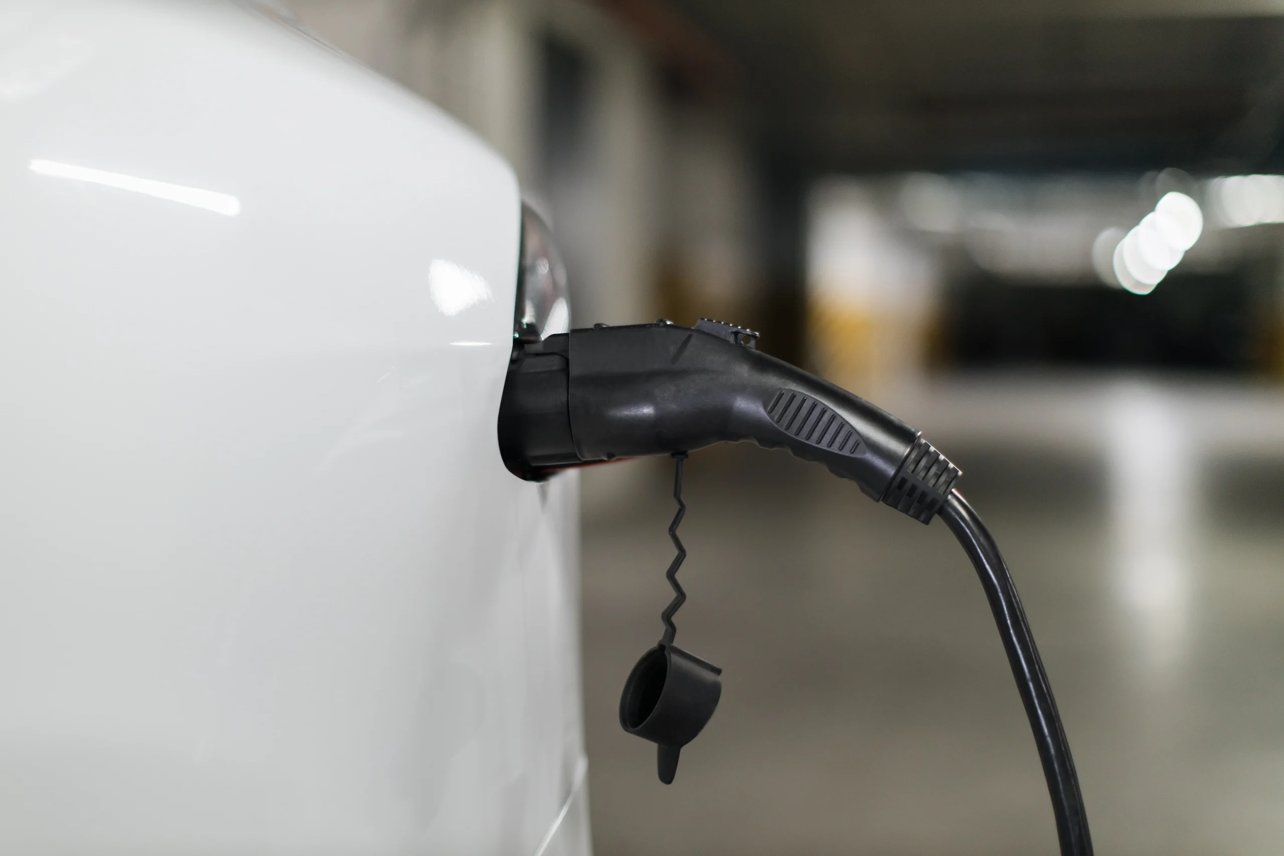 A charging cable is plugged into the side of a white electric vehicle