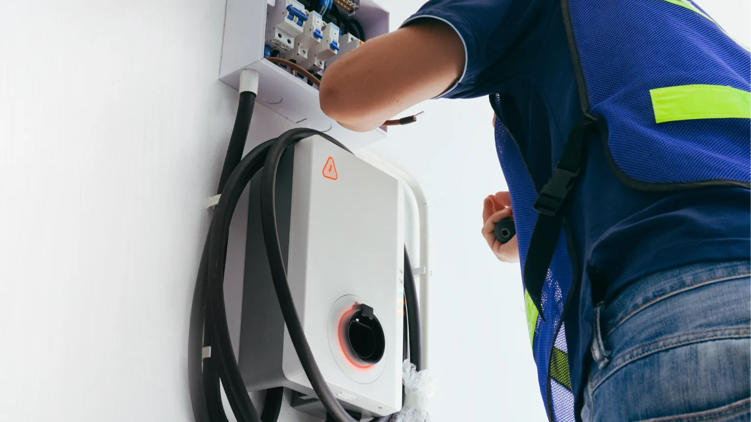 A technician installs an electric charging station on a wall
