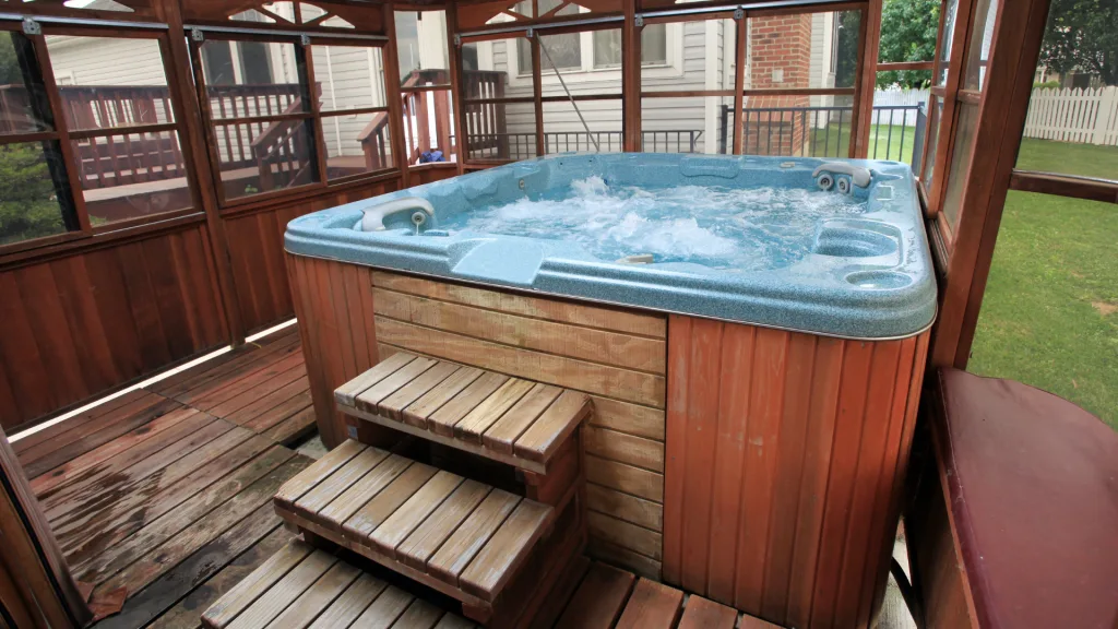 A wooden hot tub with bubbling water sits on a deck