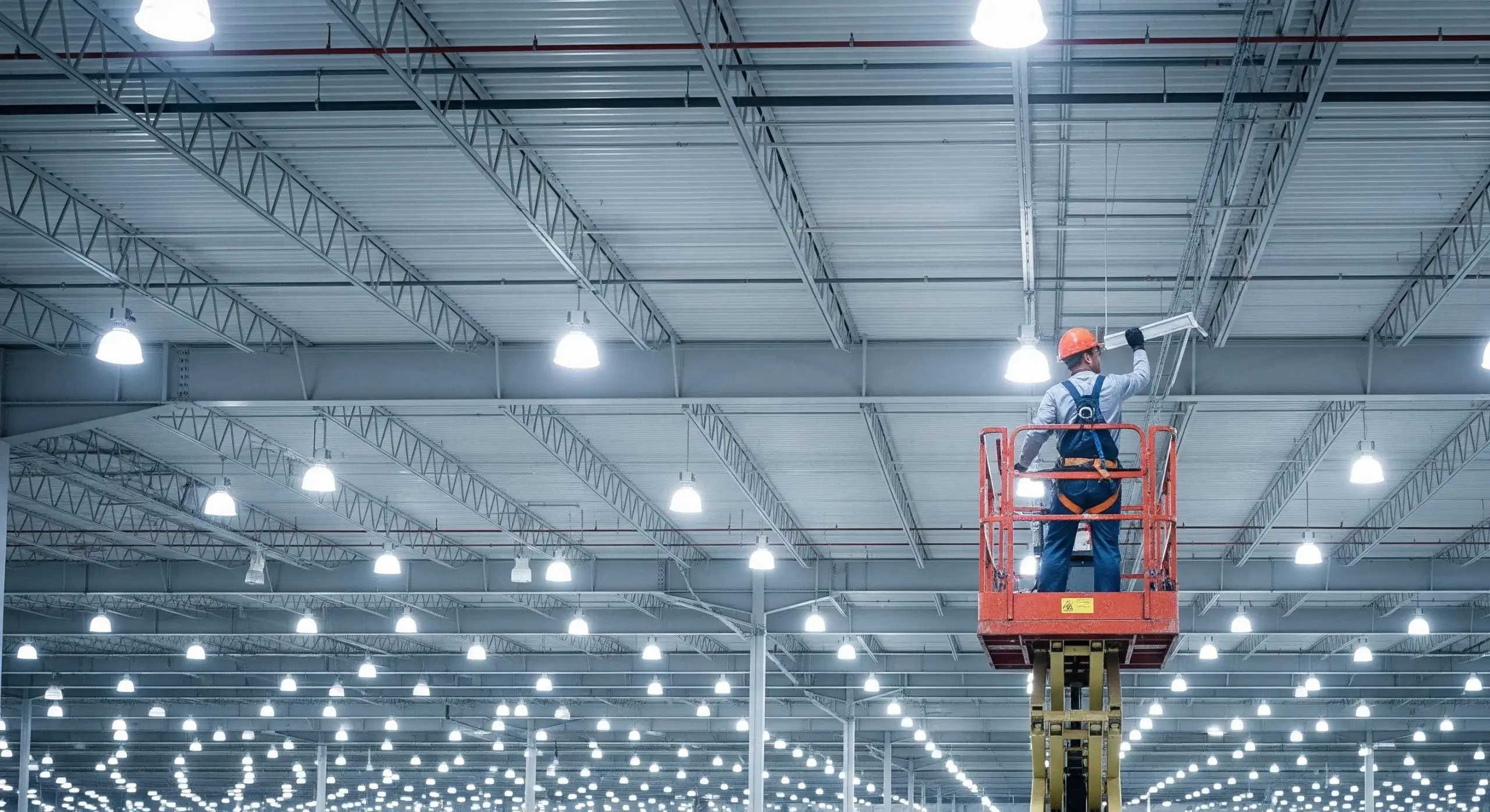 A worker adjusts commercial lighting in a spacious Calgary industrial setting