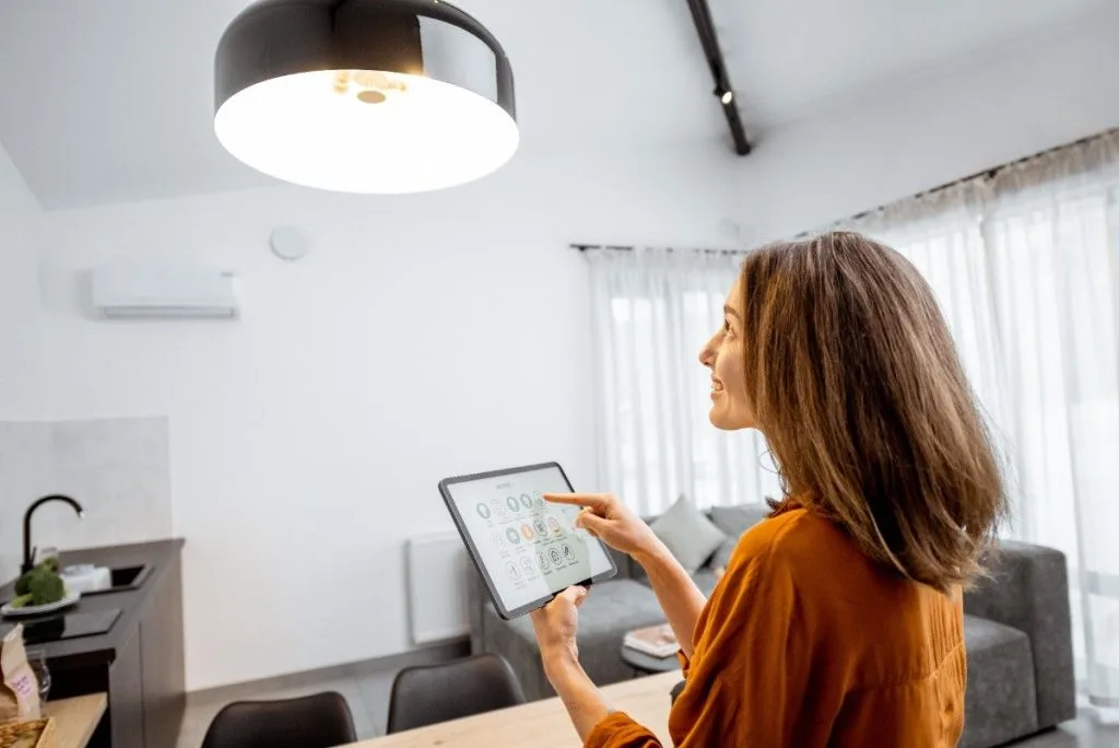A woman points to a tablet while standing in a bright, modern living space