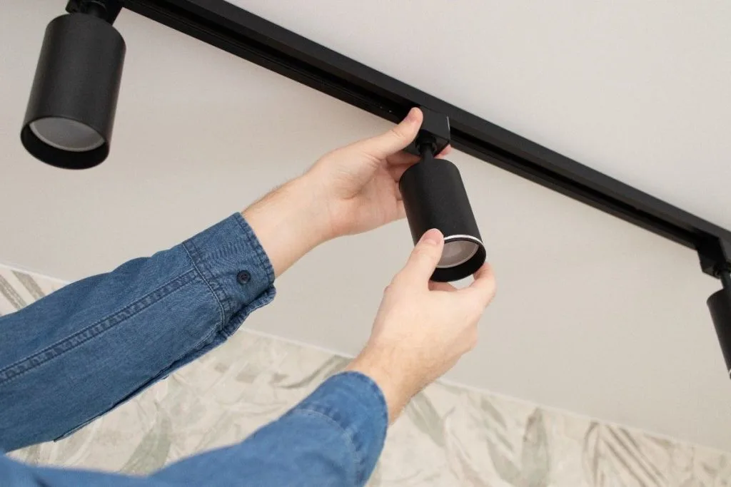 A person is installing a light fixture on a ceiling