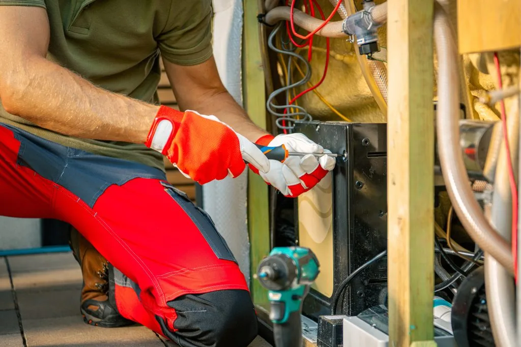 A person in red pants and gloves is working on electrical equipment