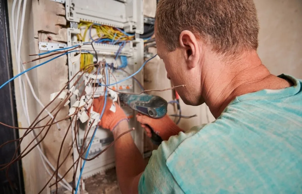 Technician inspecting electrical wires in a panel for permanent holiday lights installation